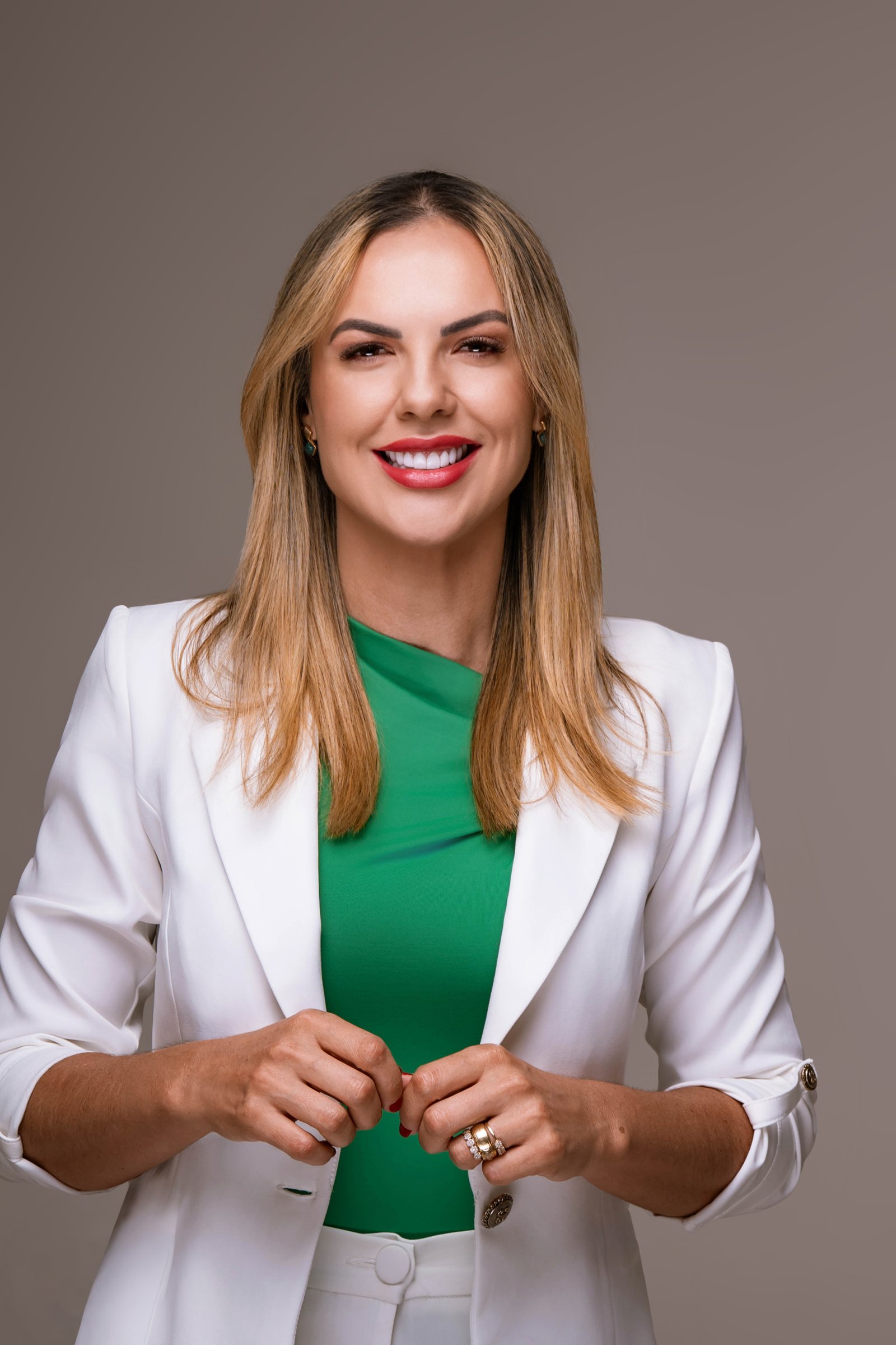 Retrato de Karen Rocha com blazer branco e blusa verde