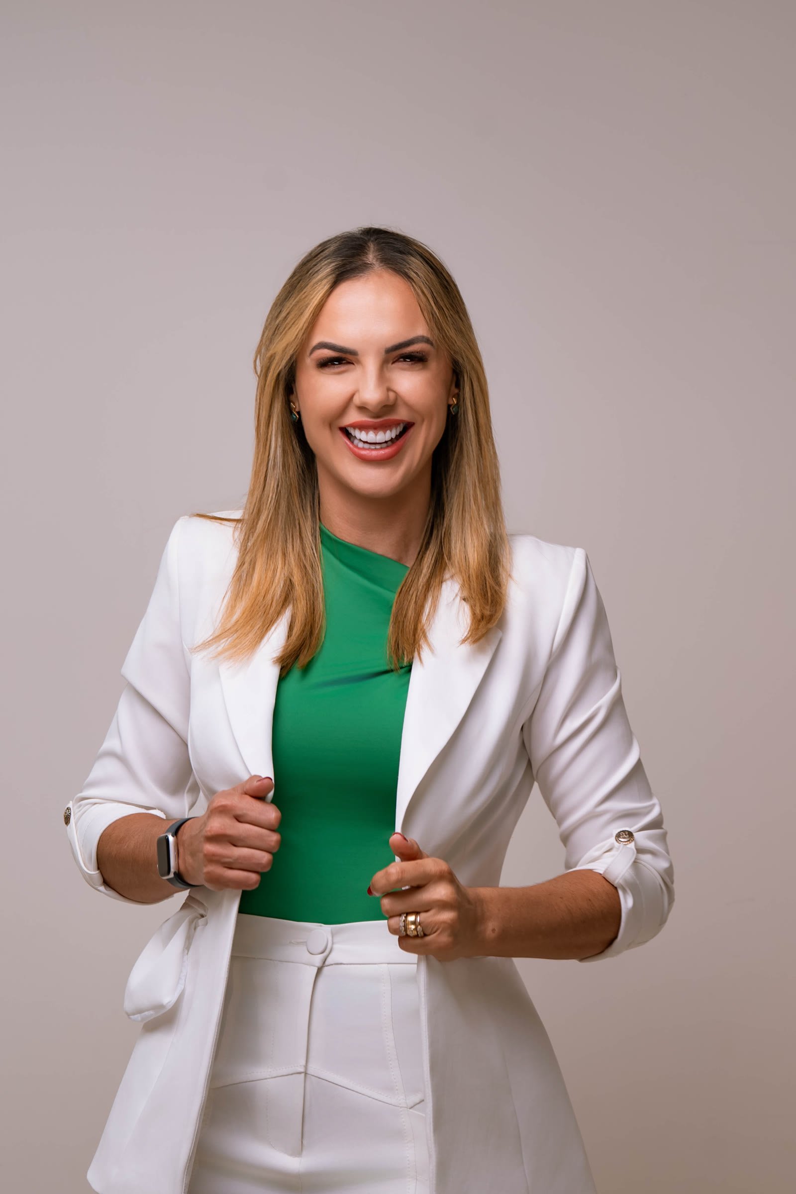 Karen Rocha sorrindo, vestindo blazer branco e camiseta verde